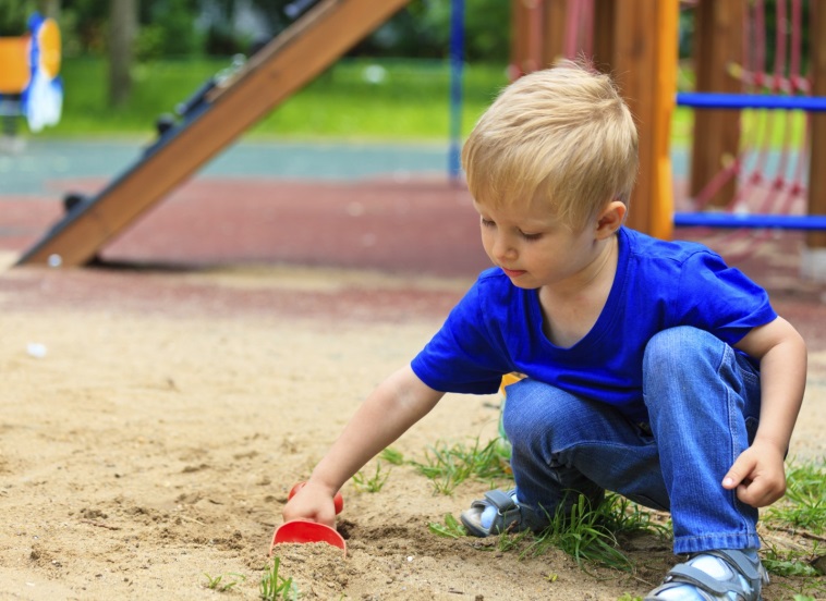 kindje speelt met schepje in zand