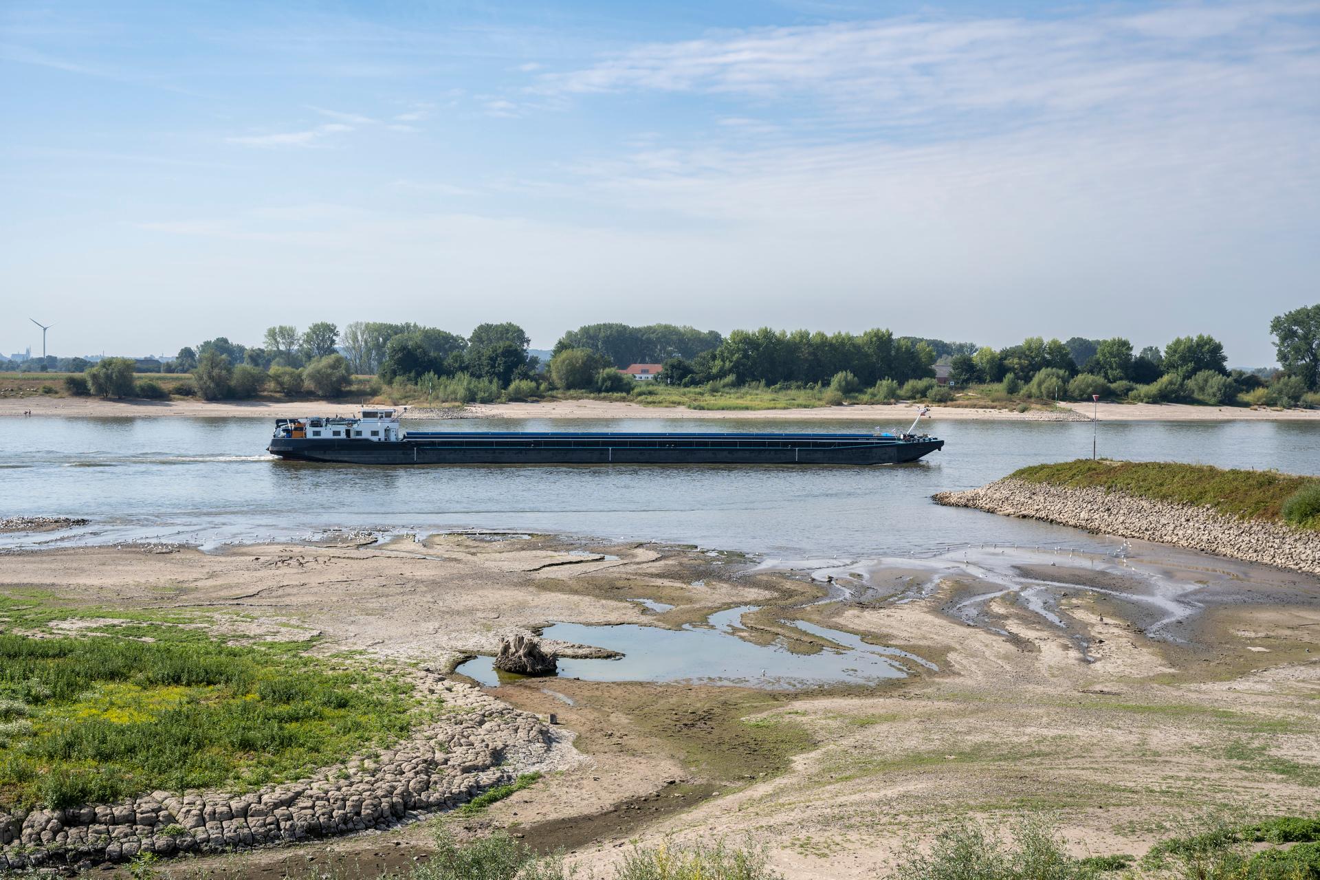 Een vrachtboot op de rivier bij laagstaandwater. De drooggevallen rivierbedding is zichtbaar