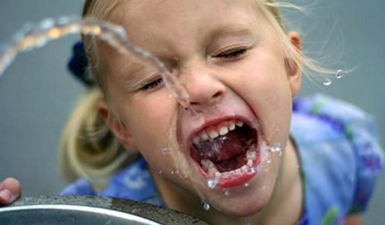 meisje drinkt uit kraan; water kan lood en nikkel bevatten